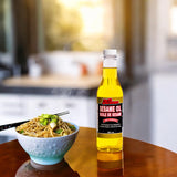 A bottle of Kissan Sesame Oil 360ml with a bowl of noodles beside