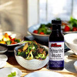 Bottle of Kissan Tamarind Sauce 350ml a salad behind it and some food in the backjground