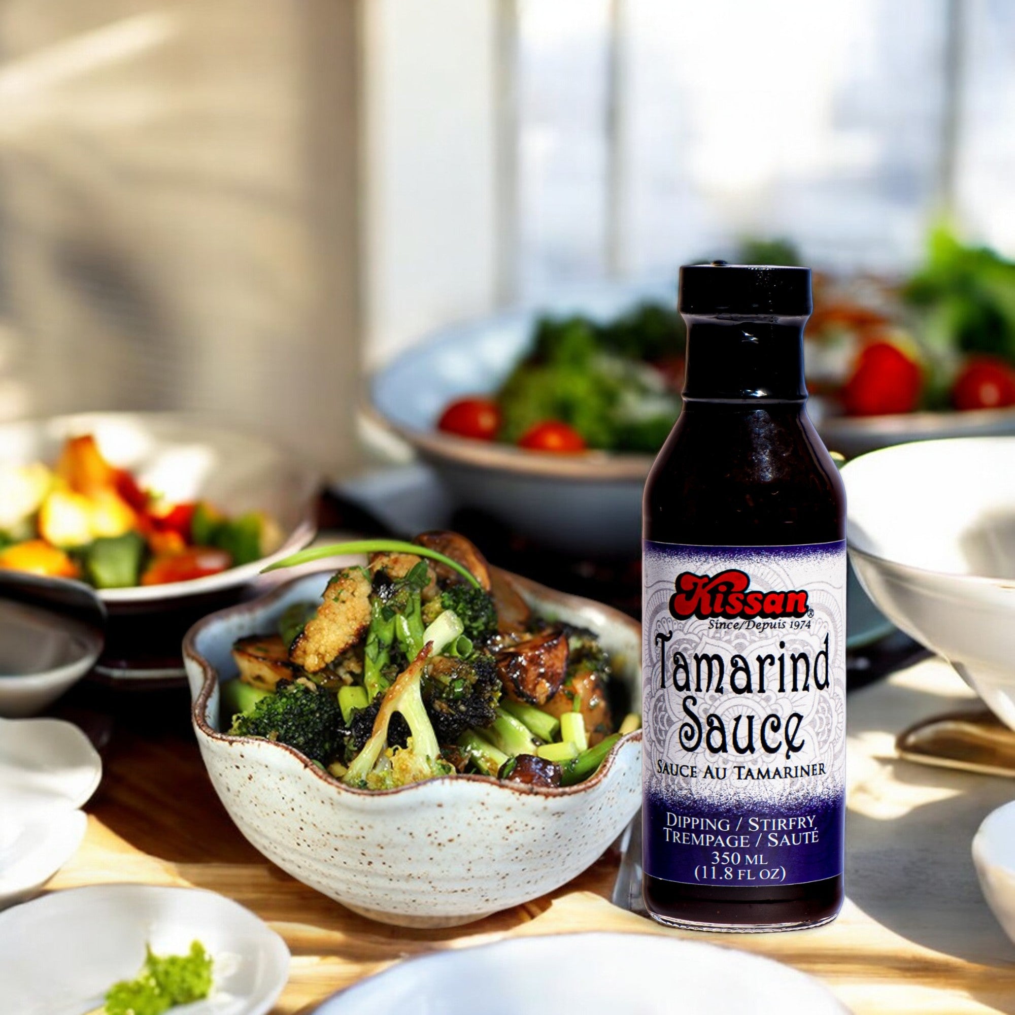 Bottle of Kissan Tamarind Sauce 350ml a salad behind it and some food in the backjground